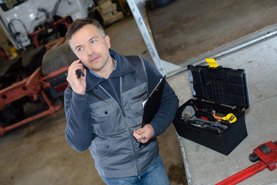 mechanic on the phone holding clipboard