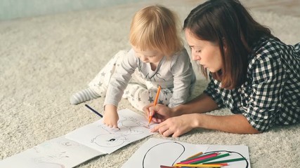 Mother with little daughter draws in album with pencils - Powered by Adobe