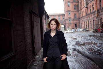 Sad red-haired girl on the background of industrial landscape. Woman walking