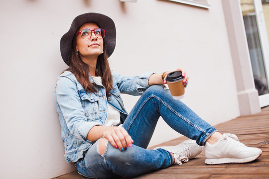 Young attractive hipster girl sits on terrace with coffee