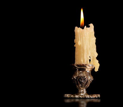 burning old candle vintage Silver bronze candlestick. Isolated Black Background.