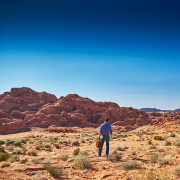 lone man with suitcase standing in desert alone