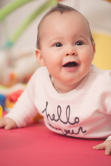 Eight months old baby girl playing with colorful toys on a floor