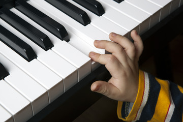 Obraz premium the hand of a little boy on the piano keys