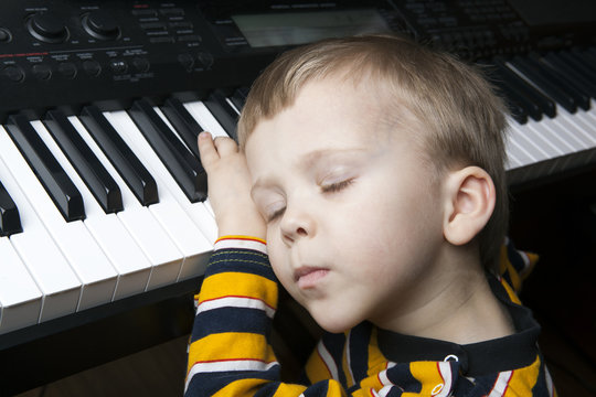 sleeping little boy sitting at the piano