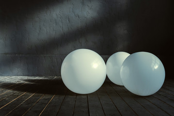 Three big balloons lying in the dark lighted room