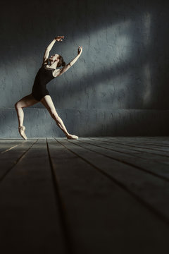 Charismatic young ballet dancer training in the black colored room