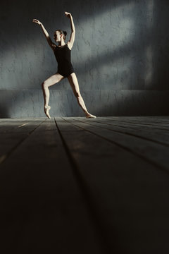 Steady ballet dancer training in the black colored room