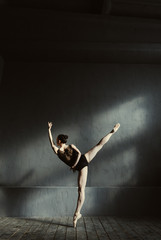 Flexible ballet dancer stretching in the dark lighted studio
