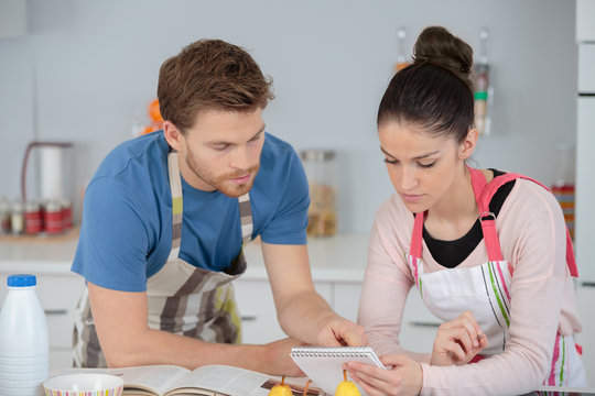 Young Couple Following A Recipe In A Kitchen