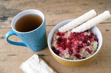 Healthy breakfast, vegetarian. Oatmeal with cranberries, sandwich with cream cheese, coconut sticks, tea.