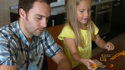 Family with their little daughter playing the board game