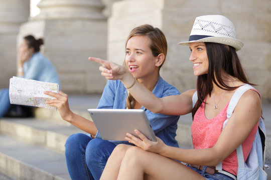 cheerful tourist female friends taking photos of themselves