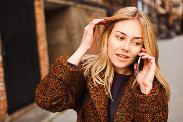 Busy and beautiful woman smiles talking phone outdoors wearing casual