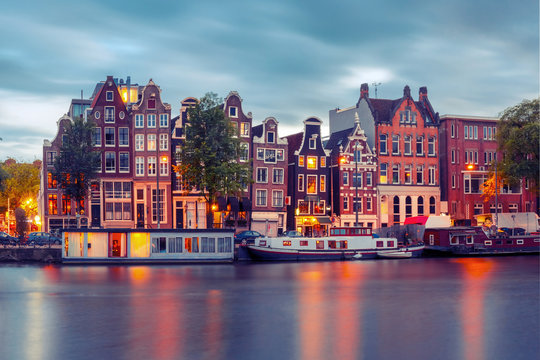Amsterdam canal Amstel with typical dutch houses and boats during twilight blue hour, Holland, Netherlands. Used toning