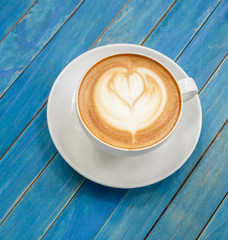 Top view hot latte coffee in white cup on blue vintage wooden ta