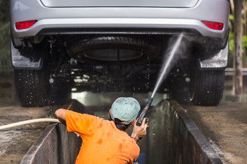 Man spraying pressure washer for car wash in car care shop. Focu