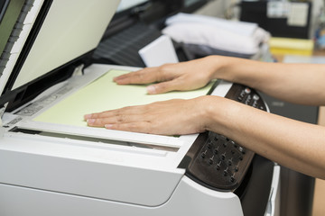 woman hands putting a sheet of paper into a copying device