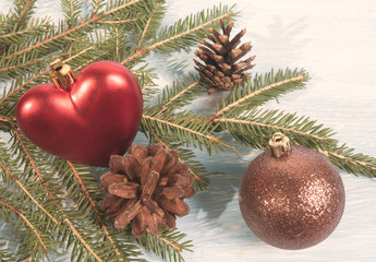Christmas tree branch on wooden background with heart, Christmas ball and pine cones