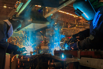 Team workers are welding in factory