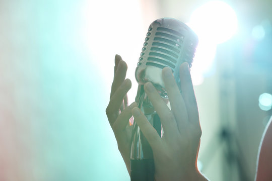 Female hands holding retro microphone, close up