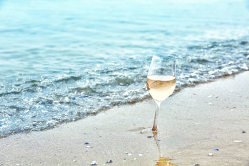 Glass of wine on sea shore, closeup