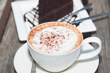 chocolate cake with coffe on plate on wood table
