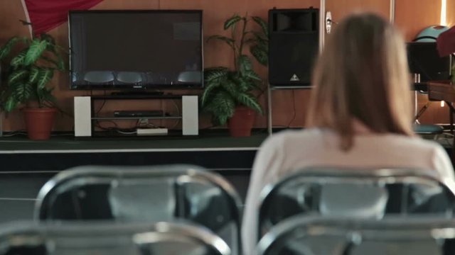 Woman watching TV in the empty conference hall of cruise ship