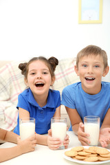 Obraz na płótnie Canvas Happy children with glasses of milk at table