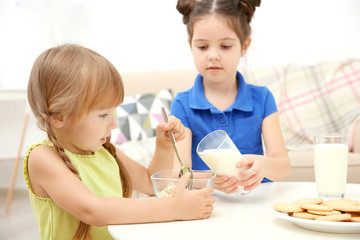 Obraz na płótnie Canvas Two little girls with milk and cornflakes