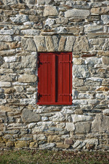 painted red wooden shutters on old stone wall