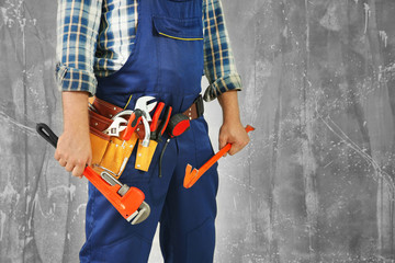 Plumber with tools against grunge background, close up view