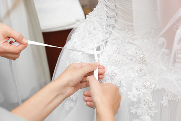 Obraz na płótnie Canvas Women lacing white wedding dress