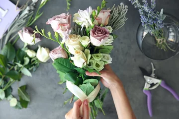 Foto op Plexiglas Bloemenwinkel Vrouwelijke bloemist die mooi boeket maakt bij bloemenwinkel