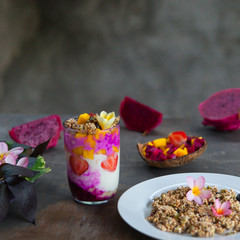 Still life of granola, colorful smoothie in glass jar and tropical fruits on dark shabby background.