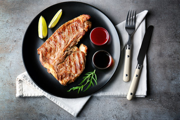Tasty grilled steak with cranberry sauce, lime and arugula on plate