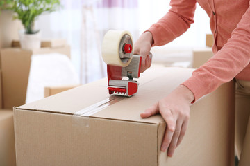 House moving concept. Closeup of woman packing cardboard box