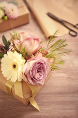 Handcrafted gift box with flowers and scissors on wooden table