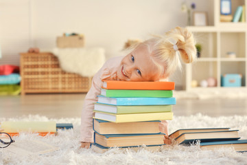 Small girl with many books on carpet
