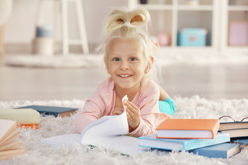 Small girl with many books on carpet