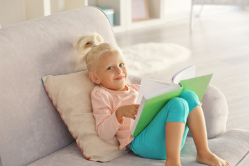 Small girl reading book on couch