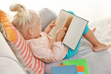 Small girl reading book on couch