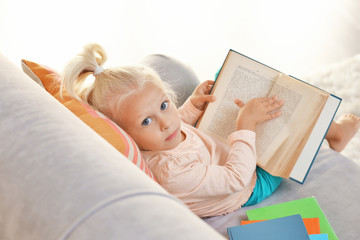 Small girl reading book on couch