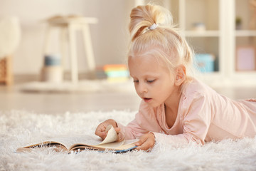 Fototapeta premium Small girl reading book on carpet