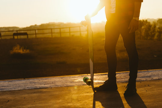 Man with skateboard standing on hill