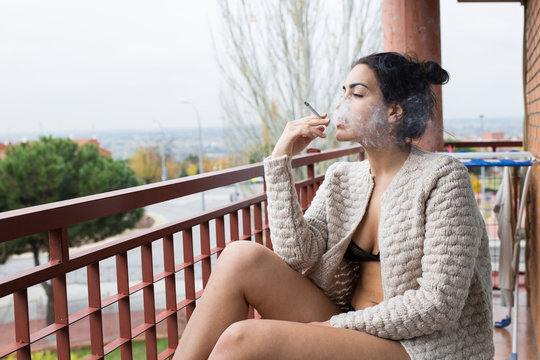 Female in lingerie and cardigan smoking