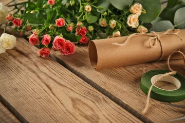 Poster de jardin Fleuriste Beautiful flowers and packaging materials on wooden background