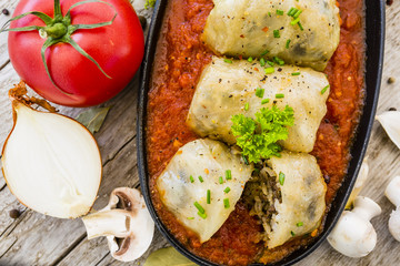 Stuffed cabbage with rice and mushroom with meat in tomato sauce on wooden rustic background.