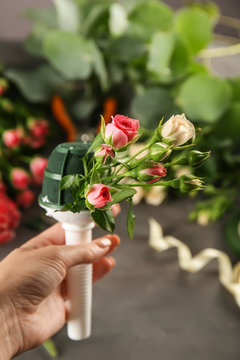 Female hand holding beautiful bouquet of flowers on dark background