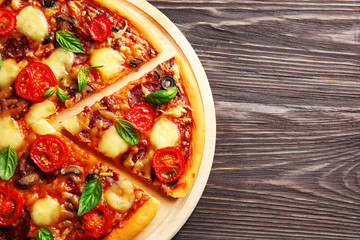 Fresh pizza with tomatoes, cheese and mushrooms on wooden background